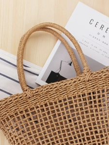 Handcrafted hollow woven straw handbag in natural brown for boho beach vacation style