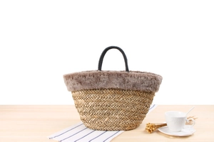 Detail of hand-woven straw tote bag with brown faux fur trim and black rope handles