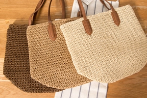 Trois sacs cabas en corde de papier tressée marron, kaki et crème sur bois