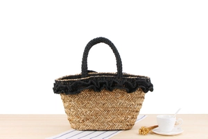 Detail shot of the handwoven straw beach bag featuring black lace trim and rustic textures