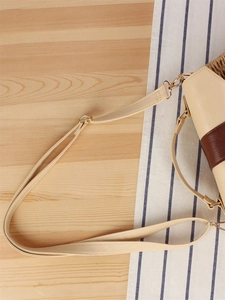 Handwoven straw tote bag with adjustable beige leather strap and gold metal buckles