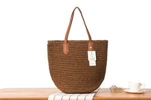 Détail du sac cabas en corde de papier marron tressée avec des poignées en cuir marron