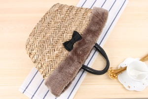Detail of woven straw beach bag with brown faux fur trim and black ribbon bow accent