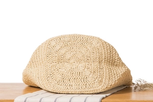 Détail du tissage radial en paille naturelle d'un chapeau de plage beige chic