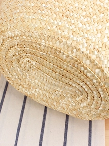 Handcrafted straw shoulder bag featuring a spiral woven base and natural texture