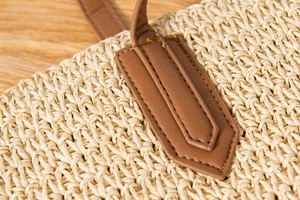 Gros plan sur la texture de paille tressée et le raccord en cuir marron cousu main