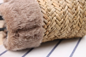 Close-up of hand-woven straw bag featuring plush brown faux fur trim and natural textures