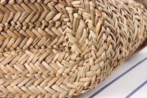 Macro shot of handcrafted natural straw weaving texture on a rustic beach tote bag