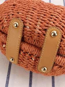 Borsa intrecciata arancione con cinturini in pelle e borchie dorate su sfondo testurizzato