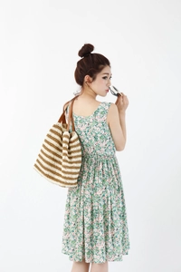 Detail of a hand-woven striped tote bag with brown leather handles and a straw texture