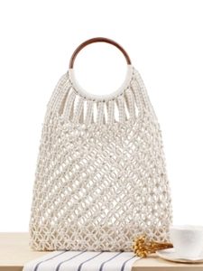Handmade macrame woven bag with dark round wooden handles in a bohemian beach style