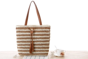 Detail of striped crochet beach tote with brown leather handles and tassel drawstring