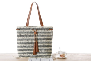 Detail of striped crochet tote bag with brown leather tassels and natural woven texture
