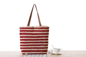Detail of red and white striped crochet tote bag with brown leather straps and drawstring