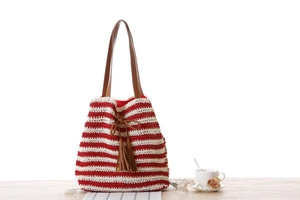 Detail of red and white striped crochet beach bag with brown leather handles and tassels