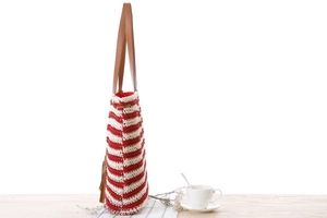 Detail of red and white striped crochet beach tote with brown leather straps and tassel