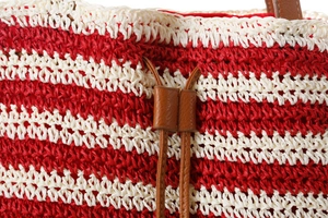 Close-up of red and white striped crochet bag with premium brown leather drawstring detail