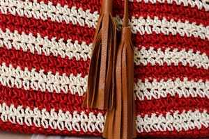 Close-up of red and white striped crochet handbag texture with leather tassels