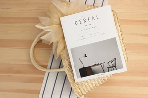 Detail of woven straw tote bag featuring a large tulle bow and round handles on wood