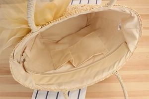 Detail view of woven straw tote bag interior showing inner pockets and yellow organza bow