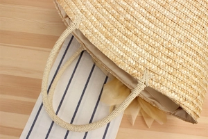 Detail of hand-woven straw tote bag with yellow mesh bow and herringbone texture