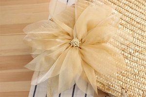 Close-up of elegant silk flower with pearls on a woven straw beach bag detail