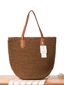 Sac cabas de plage en paille tressée marron avec anses en cuir sur table en bois
