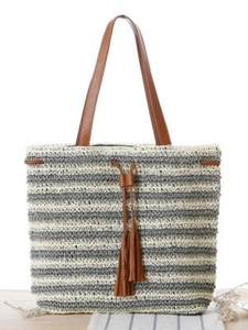 Striped crochet tote bag with brown leather handles and tassel for beach vacations
