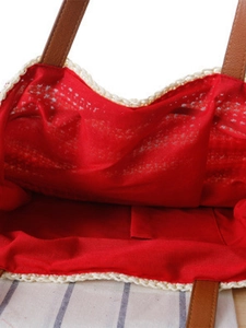 Striped crochet tote bag with red lining and brown leather straps for beach holidays