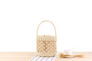 Detail of woven straw bucket bag with floral cut-out patterns and fabric lining