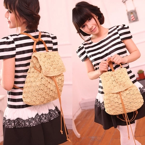 Detail of woven straw backpack with brown leather straps and hollow floral pattern