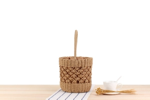 Detail of hand-woven straw bucket bag with hollow grid pattern and inner drawstring pouch