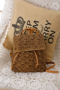 Detailed view of handmade woven straw backpack with hollow mesh pattern and drawstring
