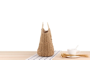 Detailed close-up of woven paper rope texture and circular wooden handles on a beach bag