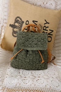 Close-up of olive green hand-crocheted backpack with leather drawstring and flap closure