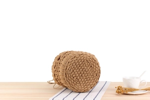 Detailed view of hand-woven bucket bag featuring intricate textured knit on wood table