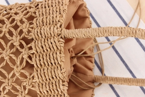Detailed close-up of handmade woven straw bucket bag with drawstring liner and handle