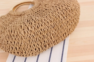 Detailed close-up of handmade woven paper rope bag with smooth round wooden handles