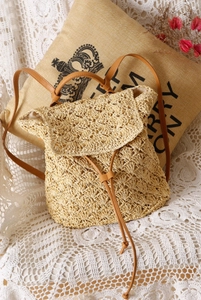 Detailed macro view of woven beige straw backpack with brown leather drawstring closure