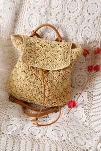 Detailed view of woven straw backpack with crochet patterns and brown leather straps
