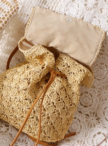 Detail view of woven straw backpack showing inner lining, drawstring, and magnetic clasp