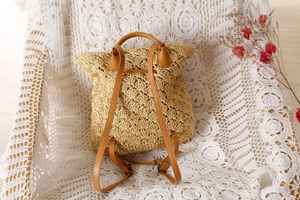 Detailed close-up of woven straw texture and bohemian hollow pattern on backpack