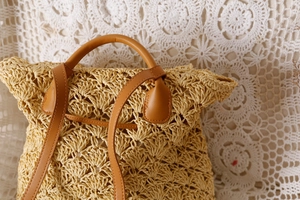 Detailed view of woven straw texture and premium brown faux leather straps on a beach bag