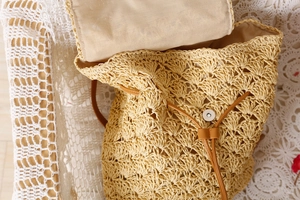 Detailed macro view of woven straw backpack with inner lining and brown leather drawstring