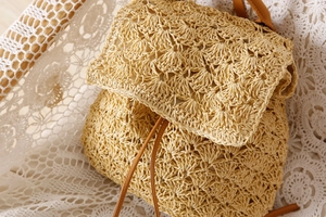 Detailed close-up of handmade woven straw backpack with leather drawstring closure