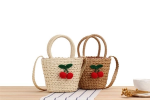 Detailed texture of hand-woven straw tote bag with cute 3D crochet cherry charm