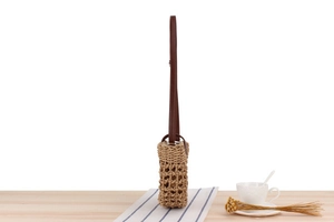 Detailed side view of handcrafted woven straw bag with slim leather shoulder strap