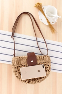 Detail of handmade woven beach bag with leather strap next to a phone for size scale
