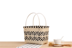 Detail of woven basket bag showing black and beige geometric pattern and white handles