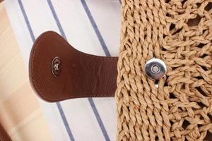 Close-up of metal magnetic clasp and leather detail on handmade woven beach bag